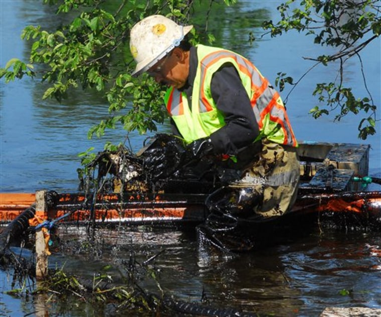 A worker lifts oil-covered debris from the Kalamazoo River in Battle Creek, Mich., on Tuesday. 